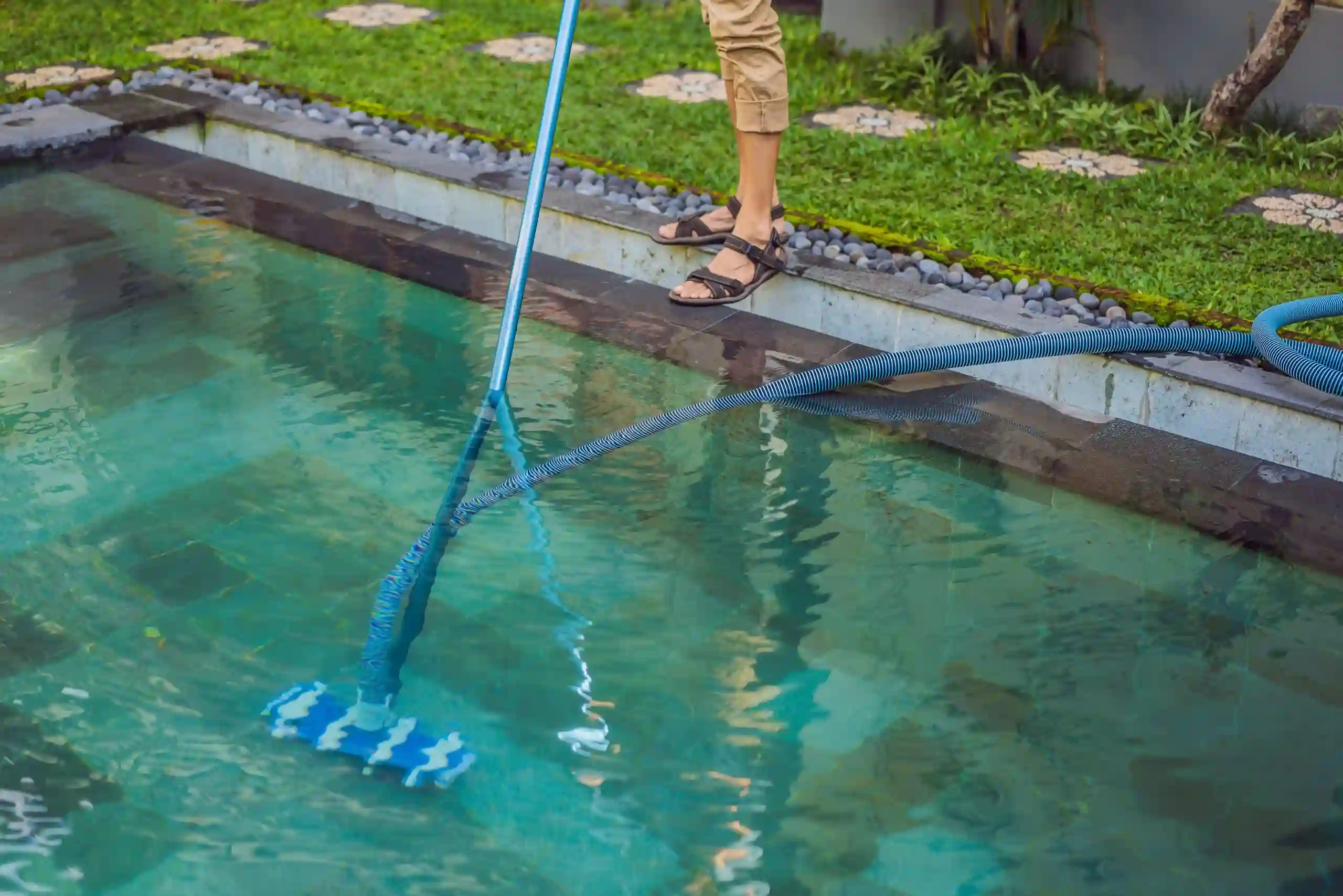 Persona limpiando el piso de una piscina